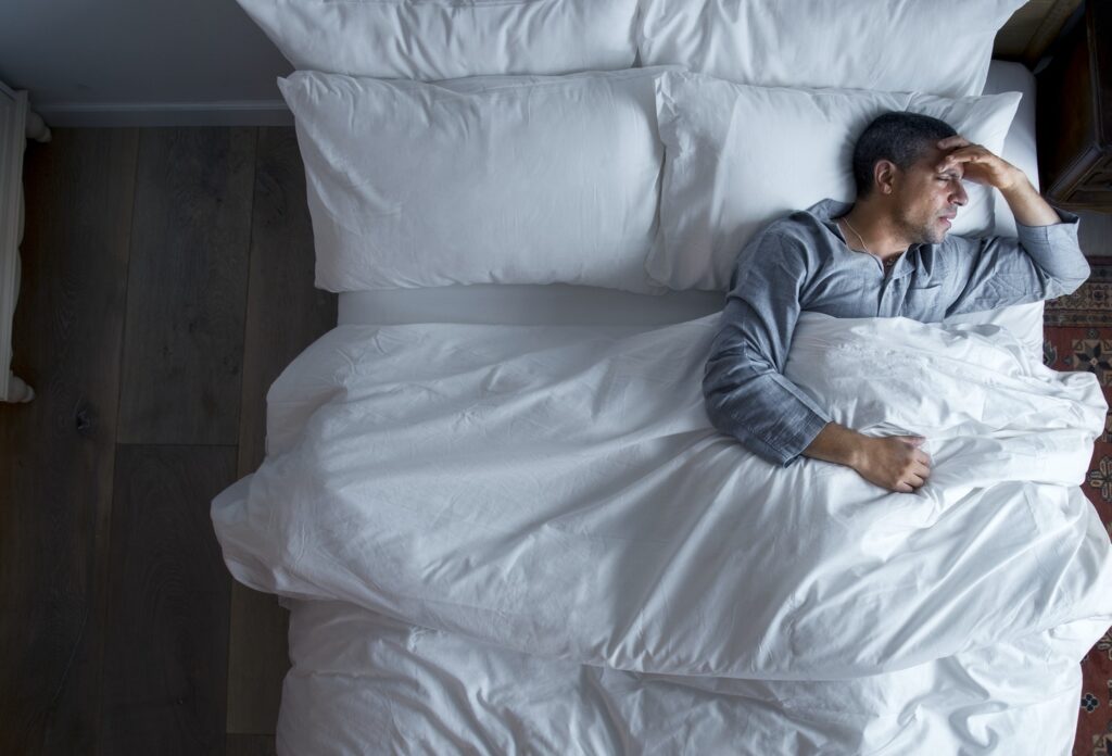 Man on bed with a headache