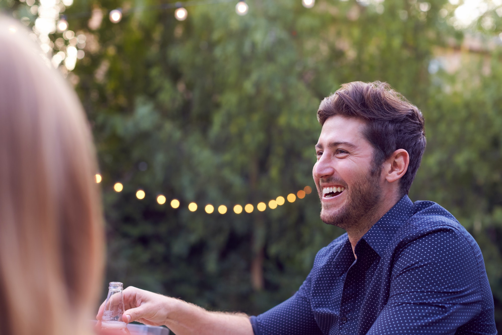 Man With Beer In Garden At Home With Friends Enjoying Summer Garden Party