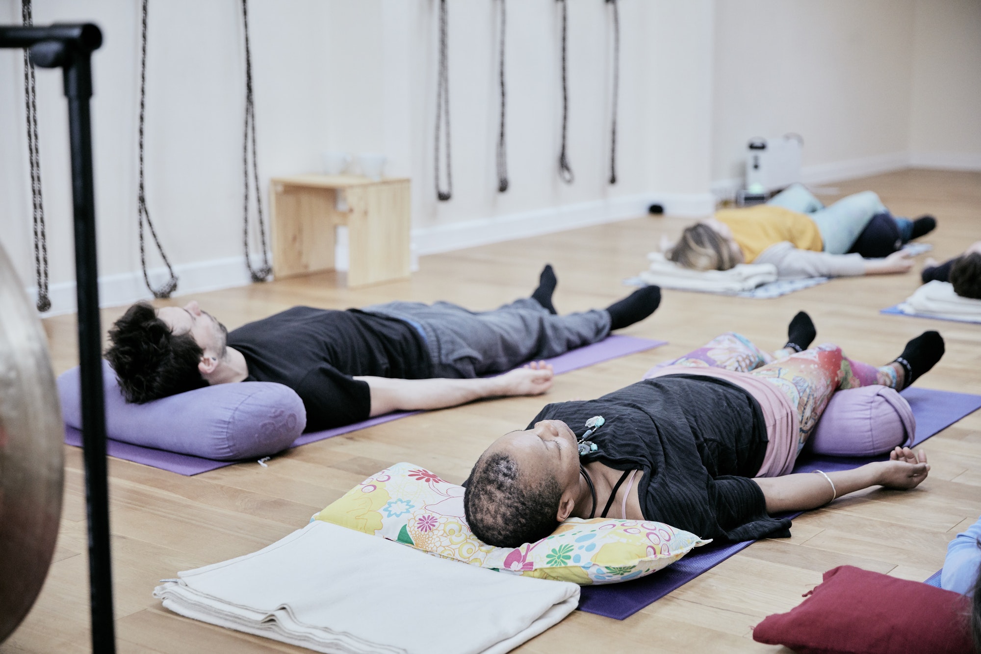 People lying down on an exercise studio floor relaxing after a sound therapy session