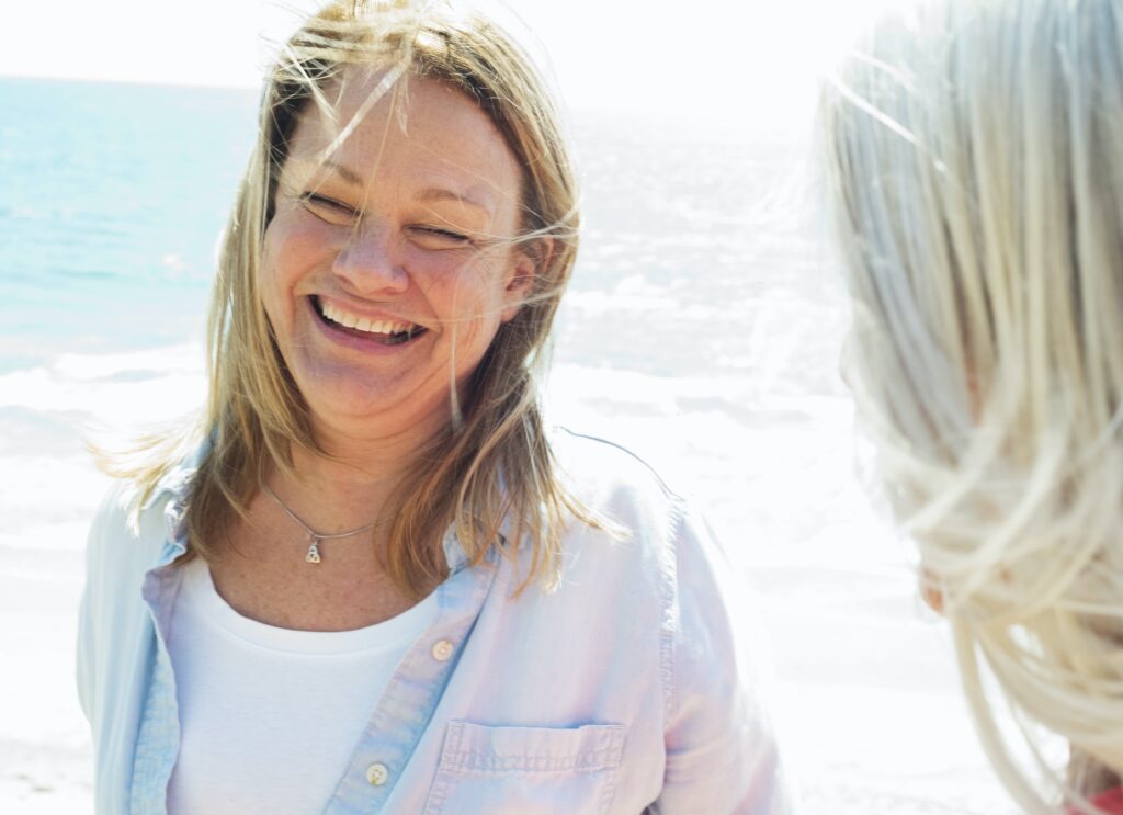 Smiling blond mature women standing by the ocean.