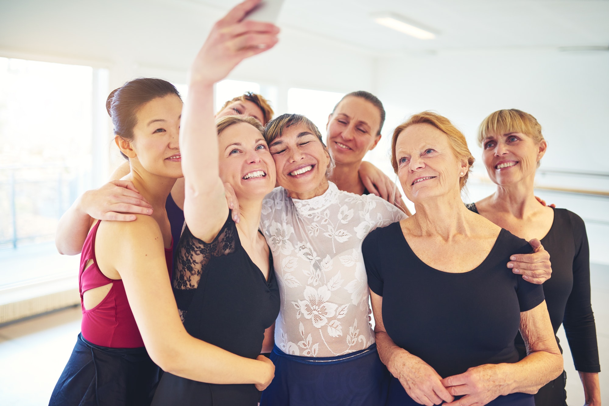 Smiling group of friends taking selfies in a dance studio