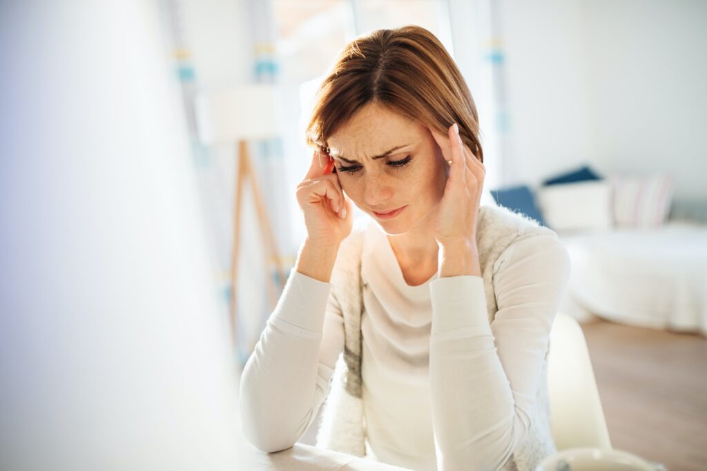 A young woman in pain sitting indoors, working in a home office.