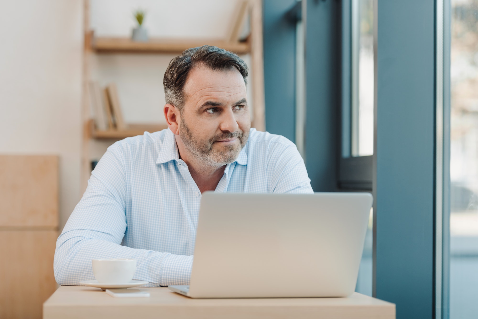 handsome mature businessman with laptop looking away