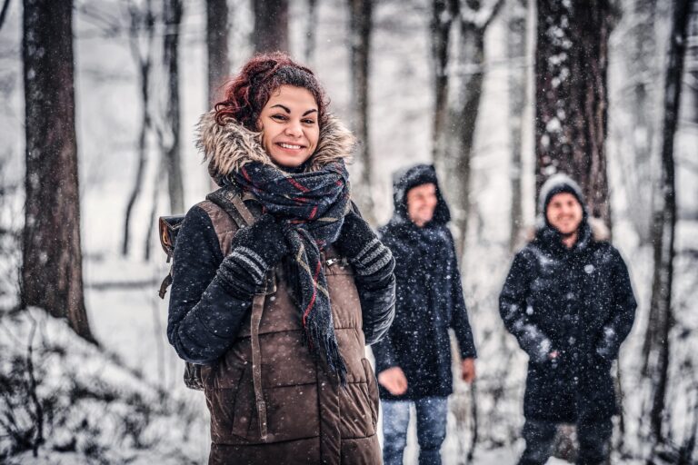 Redhead girl with friends walk in the winter in the woods