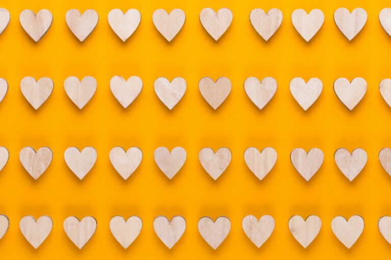 Small wooden hearts on a yellow background.