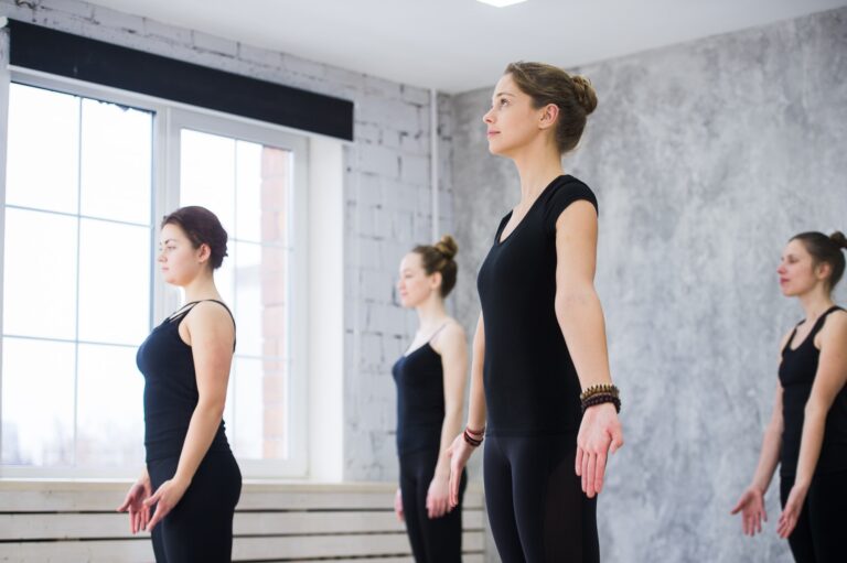 Women doing yoga sun salutation pose indoors at yoga studio