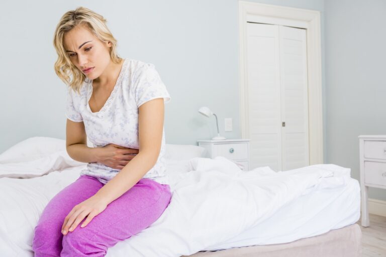 Young woman having stomach pain in bed