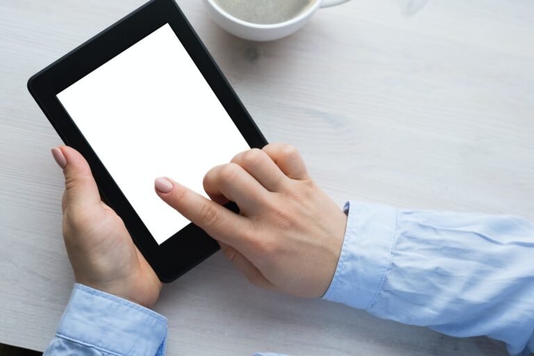 Young woman sitting by the window with an e-book