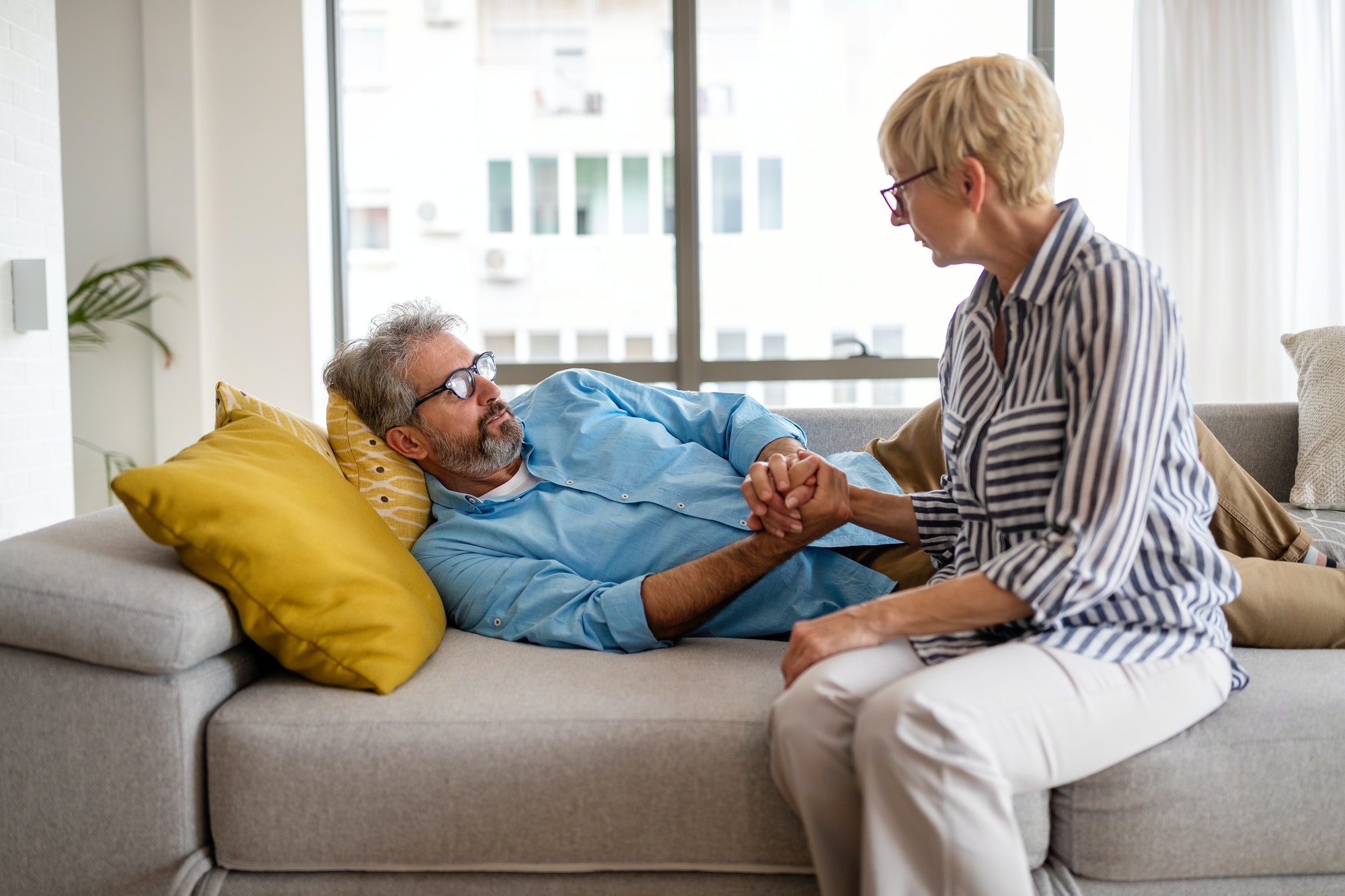 Senior woman comforting man with depression, health problem, stress at home