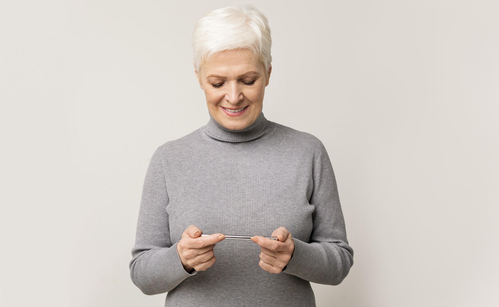 Senior woman playing video game on mobile phone and smiling