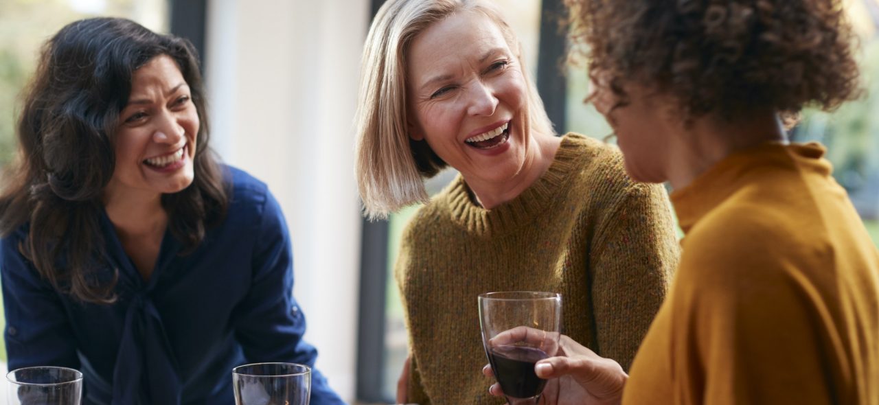 Group Of Mature Female Friends Meeting At Home To Talk And Drink Wine Together